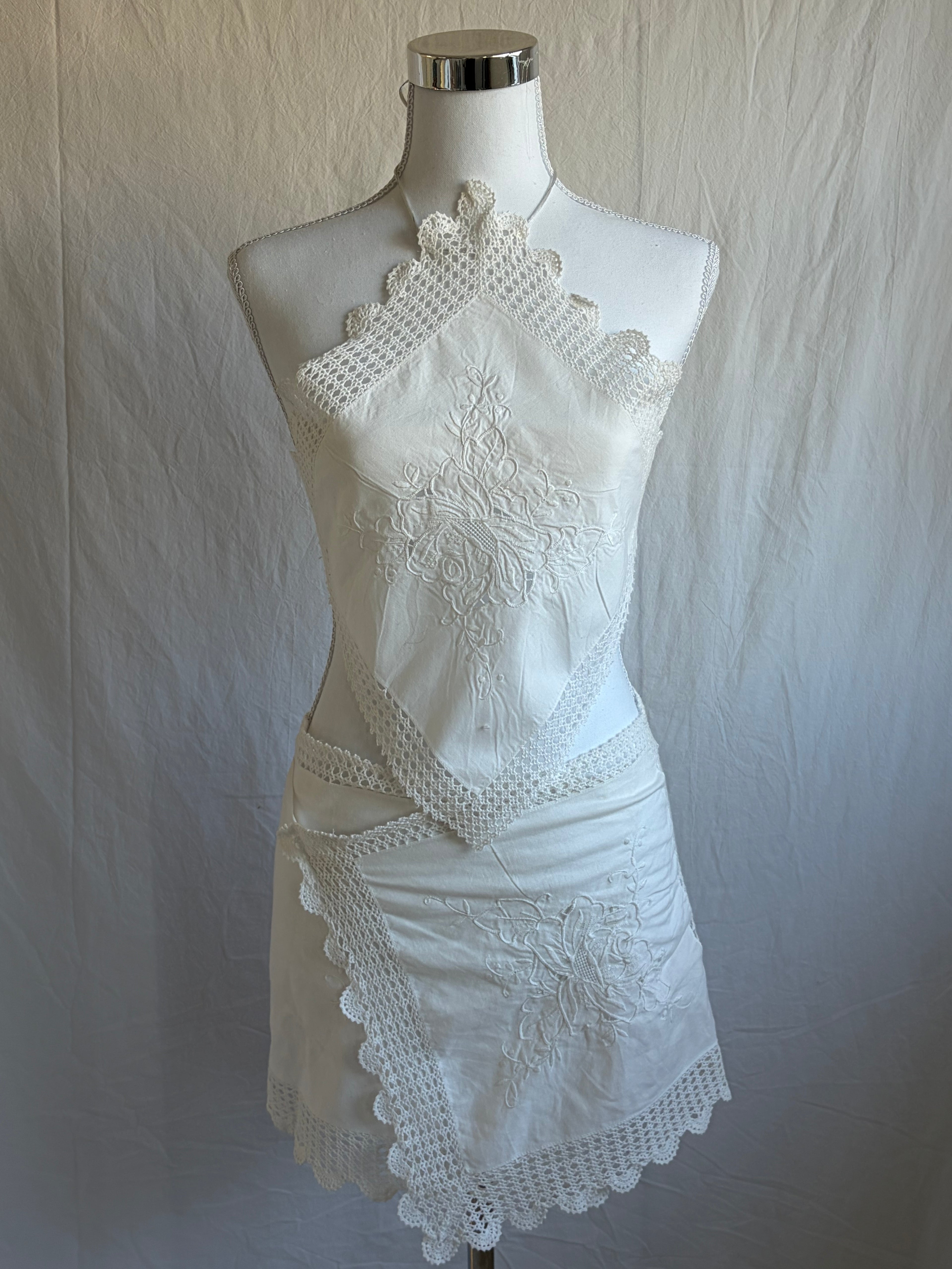 White lace dress on a mannequin against a plain background
