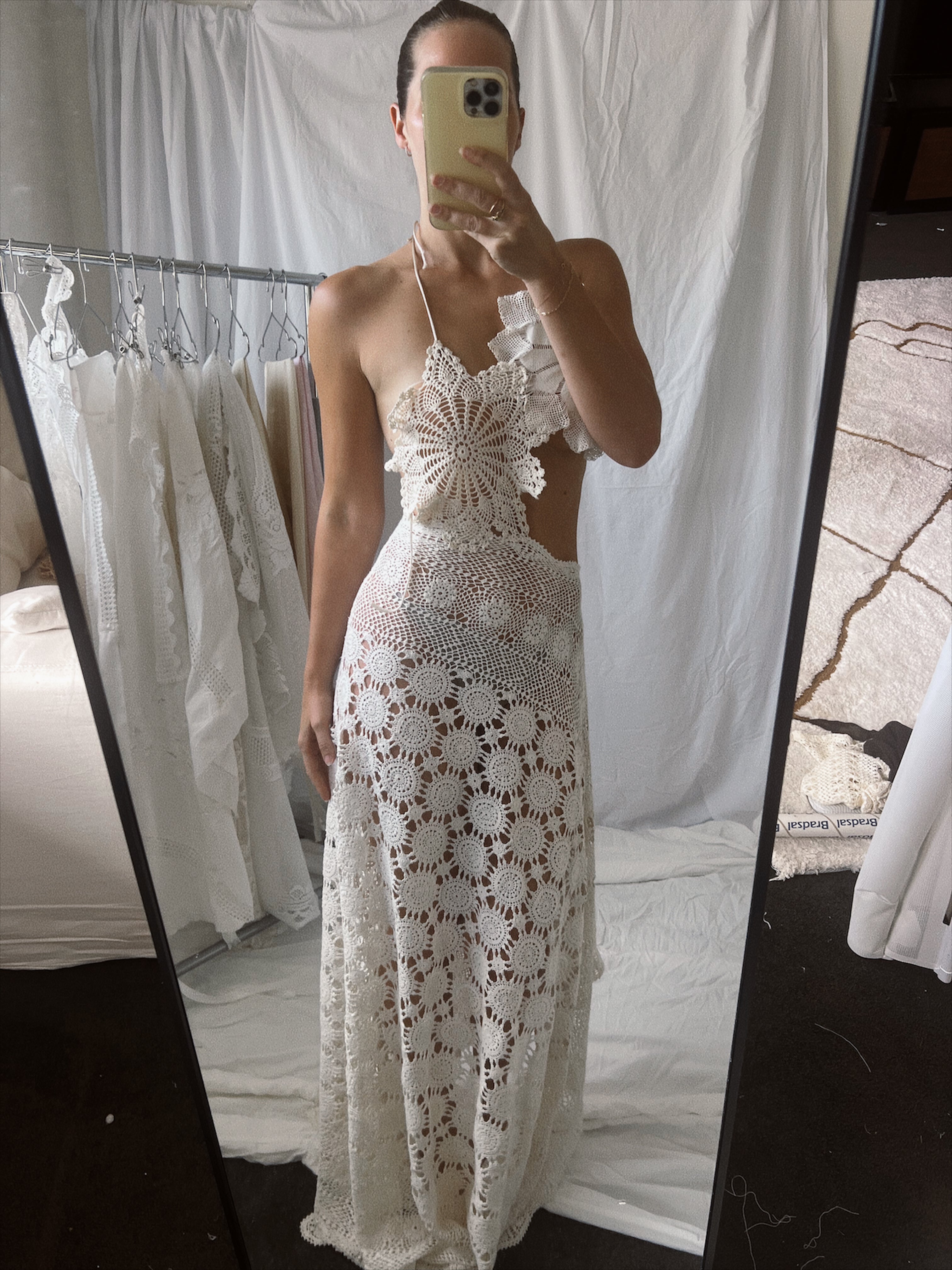 Vintage-style cream crochet two-piece set. The set includes a cropped halter top adorned with oversized three-dimensional floral appliqué details, and a high-waisted, asymmetrical maxi skirt featuring large circular crochet floral patterns.